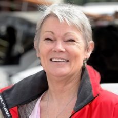 Headshot of Tracy Edwards smiling and wearing a red sailing jacket