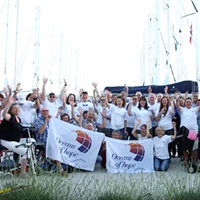 Group photo of participants in Croatia wearing white Oceans of Hope t-shirts and holding two white Oceans of Hope flags and waving