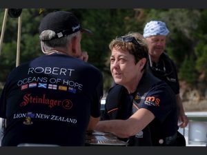 Robert talks to a fellow participant with his back to the camera showing his Oceans of Hope t-shirt. There is an island in the background.