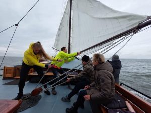 Participants on SV Poseidon pull on the rigging to adjust the sails whilst at sea