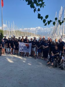 Group photo of all the participants in Turkey with the marina in the background and the white Oceans of Hope flag in the foreground