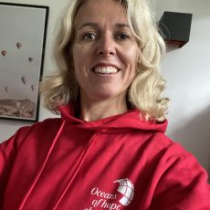 Headshot of Judith smiling and wearing a red Oceans of Hope hoodie