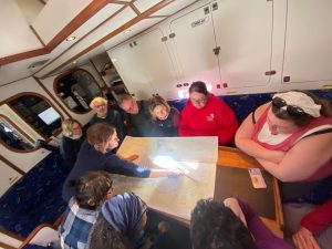 Our sailors sit around a chart table in the saloon and plan the route