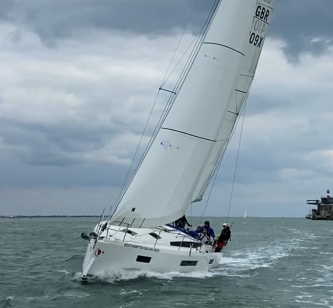 yacht sailing at 45 degree angle on the solent in front of historic gun port